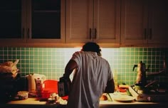 a man standing in the kitchen preparing food on the counter top, with his back turned to the camera