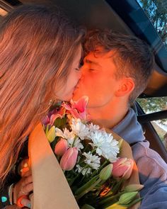 a man and woman kissing in the back seat of a car with flowers on it