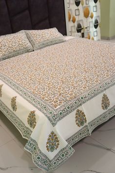 a bed with a white and green bedspread on it's headboard