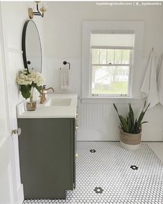 a white bathroom with black and white floor tiles