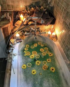 a bathtub filled with lots of yellow flowers and candles next to a fire place