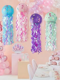 there are many jellyfish balloons hanging from the wall above the table and in the room