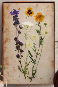 an old frame with flowers on it next to a vase