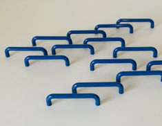 several blue handles are arranged in a row on a white surface with no one sitting at the end