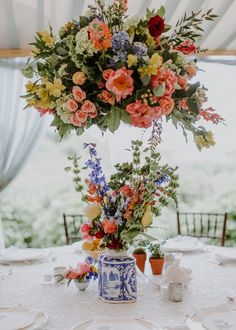 an arrangement of flowers in a vase on top of a table with plates and utensils