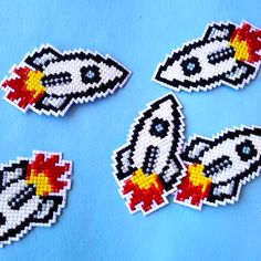 four pieces of bead art depicting rockets on a blue background with space shuttles in the middle