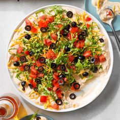 a white plate topped with a salad covered in cheese and olives next to other plates of food