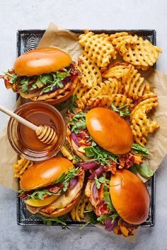 a tray filled with sandwiches and waffles next to a bowl of honey dip