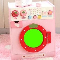 a pink toy washing machine sitting on top of a rug