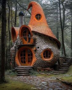 a house made out of rocks in the middle of a forest with stairs leading up to it