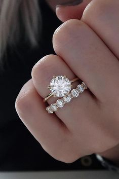 a woman's hand with two engagement rings on her finger and the ring has three diamonds in it