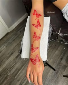 a woman's arm with red butterflies on it