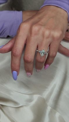 a woman's hand with blue and pink manicured nails holding a diamond ring