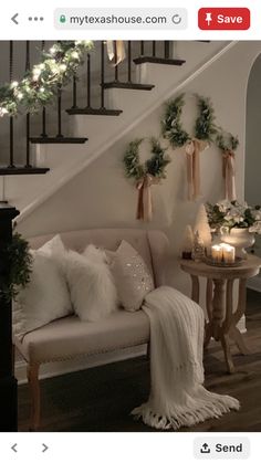 a living room filled with furniture and christmas decorations on the wall next to a stair case