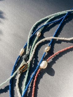 three necklaces with different colored beads on a table