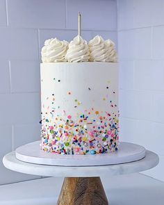 a cake with white frosting and sprinkles sitting on top of a table