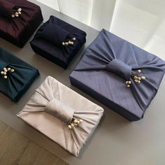 four different colored boxes with bows on them sitting on a table next to each other