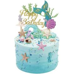 a blue birthday cake decorated with sea animals and mermaids on it's side