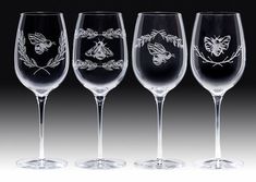 four wine glasses with designs on them are lined up against a black background and one is empty