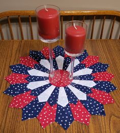 two candles sit on top of a table with red, white and blue paper flowers