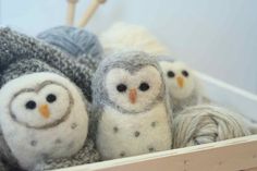 three small stuffed owls sitting next to each other in a basket filled with yarn balls