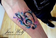 a colorful tattoo on the arm of a man with music notes and musical symbols painted on it