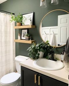 a white toilet sitting under a bathroom mirror next to a sink and a shower curtain