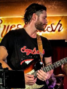 a man with dreadlocks playing an electric guitar