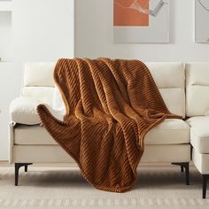 a couch with a blanket on top of it in front of a white wall and floor