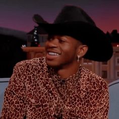 a man wearing a black cowboy hat and leopard print shirt