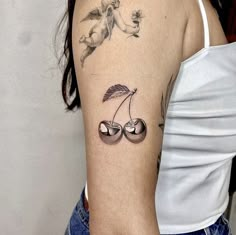 a woman's upper arm with cherries and cherries tattoo on the left shoulder