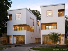 two large white buildings sitting next to each other on a lush green field at dusk