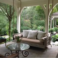 an outdoor living area with couches, tables and trees in the backgroud