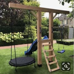 a wooden swing set with a blue slide and swings in the grass next to it