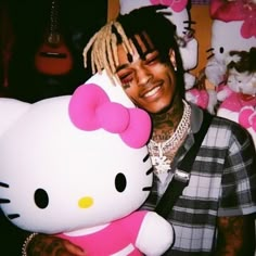 a man with dreadlocks holding a hello kitty stuffed animal in front of his face