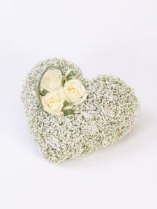 a heart shaped box filled with white roses and baby's breath flowers on a white background