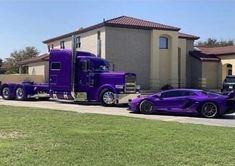 a purple semi truck parked in front of a house next to a black sports car