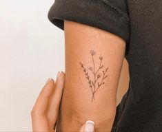 a woman's arm with a small flower tattoo on the left side of her body