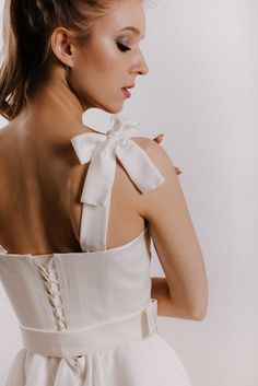 a woman in a white dress with a bow on her back