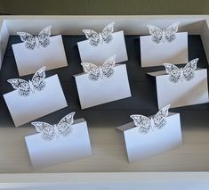 there are many white cards with butterflies on them in a cardboard box that is sitting on a table