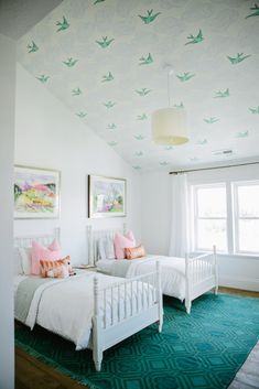 two white beds sitting in a bedroom next to each other on top of a green rug