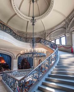 an ornate staircase with chandelier and blue curtains