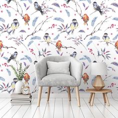 a living room with a chair and wallpaper that has colorful birds on the branches