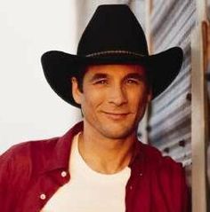 a man wearing a cowboy hat leaning against a wall