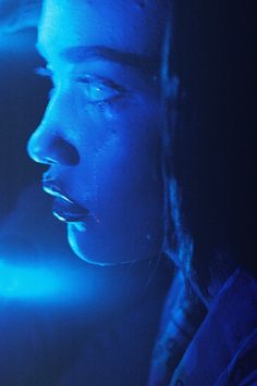 a man with his mouth open in front of a blue light and looking to the side