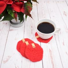 two red felt coasters sitting next to a cup of coffee on a white table