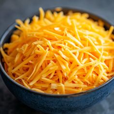 a blue bowl filled with cheese on top of a table