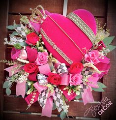 a heart shaped box with pink roses and other flowers in it sitting on a wooden surface