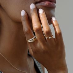 a close up of a person with rings on their fingers and one hand near her face