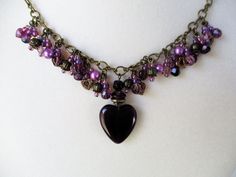 Purple Beaded Cluster Necklace Made with a purple glass heart pendant, mixed glass beads/seed beads, brass beads, toggle clasp, and chain. All dangles are handmade. 17" in length with extender chain to 18". This bold Purple Beaded Cluster Necklace will ship to you in a gift box, securely mailed in a padded envelope. Shipping same or next day, thru USPS Ground Advantage, tracking and insurance included. Once mailed, you can track your package at USPS.com. If you don’t love your new treasure, you Mixed Beads Necklace, Purple Bead Necklace, Purple Beaded, Eyeglass Chain, Cluster Necklace, Handmade Wire Jewelry, Beaded Accessories, Purple Glass, Glass Heart